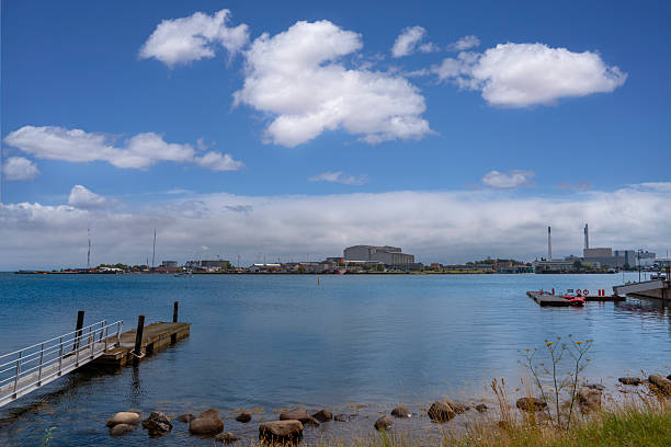Copenhagen harbor Denmark with calm sea water and industrial buildings under partly cloudy sky