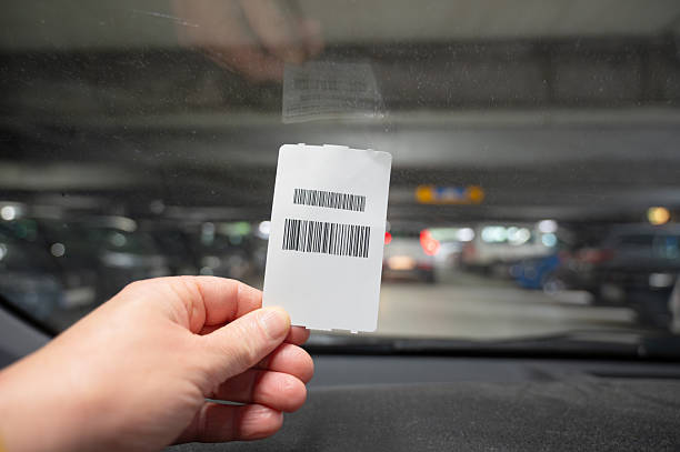Holding parking entrance and exit ticket in hand, parked car, parking and paying in garage, windshield of vehicle
