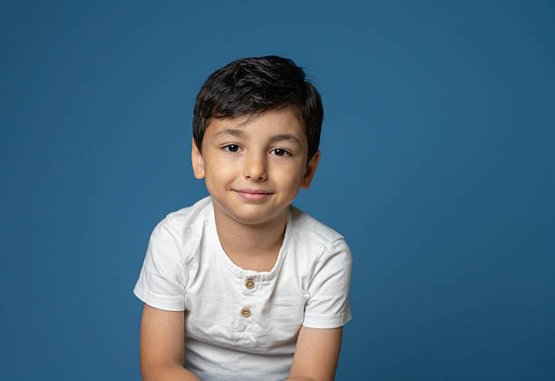 Smiling Cute little boy portrait , Studio shot, blue wall background