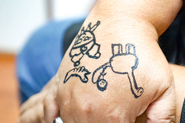Close-up of hand with childlike ink drawings of cartoon creatures and animals.