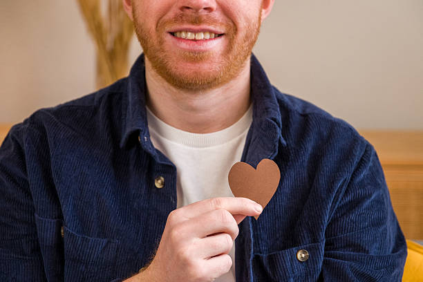 Man holding a brown heart shape, showing affection and a positive emotion