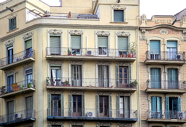 Front view of classic apartment building with balconies and shuttered windows showing urban residential lifestyle and European city architecture