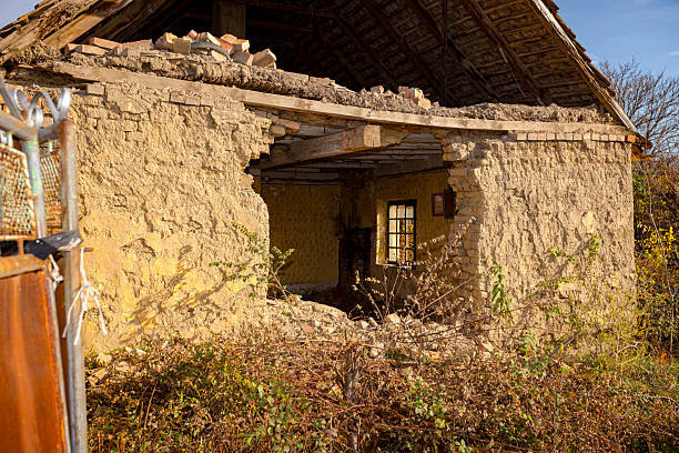 Abandoned neglected old adobe house made with bricks of mud, clay and straw with hole in wall.