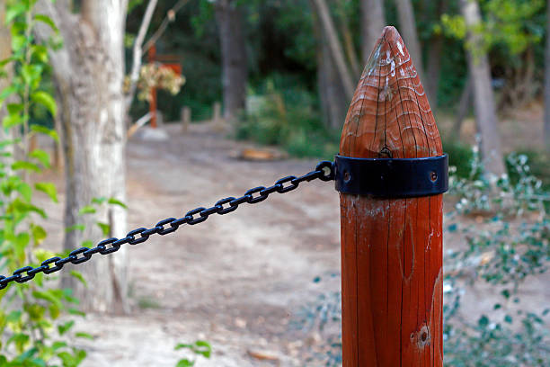 Close-up of a wooden post with metal chain in a natural setting, ideal for concepts like safety, restricted access, or rural tranquility.