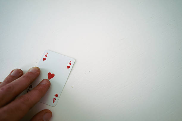 Card ace heart under hand on white table.