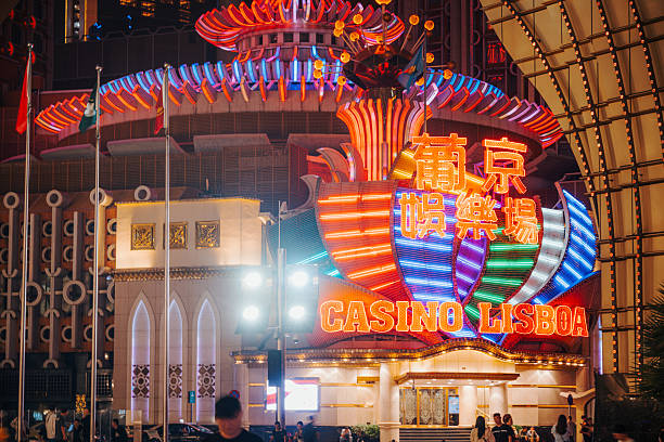 Vibrant night scene of the neon-lit Casino Lisboa in Macau, China. Bright signage and colorful lights illuminate the entrance, creating a lively urban atmosphere.