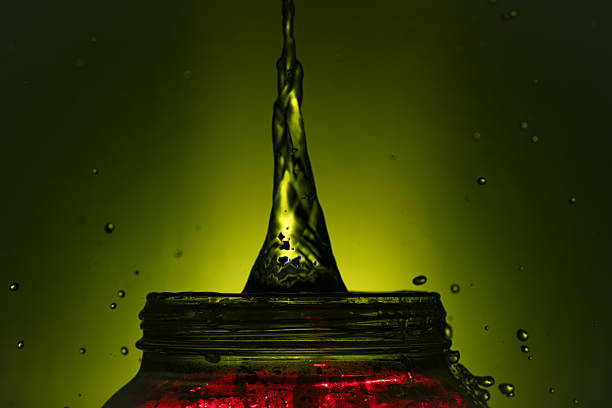 392.Close-up of liquid surface showing single bubble with blue-green lighting. Bubble is partially submerged. Light reflections and refraction highlight surface tension and fluid texture.