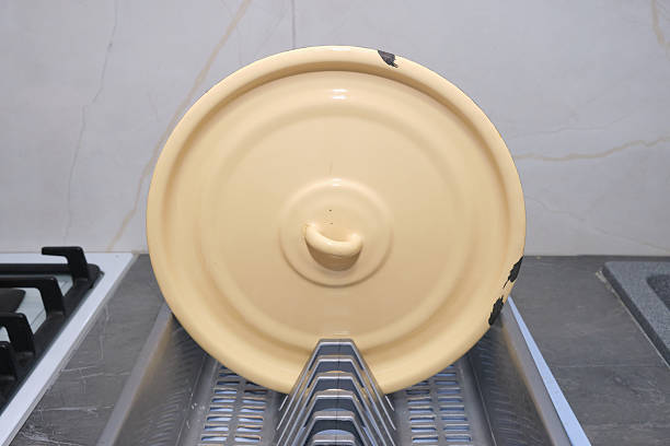 This image displays a yellow pot lid on a kitchen rack. Perfect for illustrating home cooking, kitchenware, or simple living. Use it for recipes or culinary blog posts