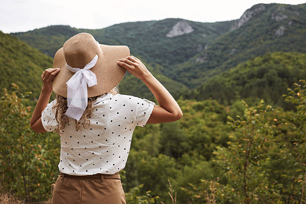 Woman standing enjoying a scenic view of green mountains during summer travel