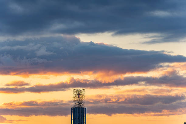 Madrid. Spain. Modern church tower silhouette with cross against a vivid sunset sky of blue and warm orange, evoking serene worship