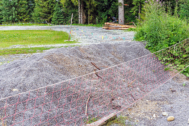 Large pile of crushed stone and gravel behind a safety net in a forest area. Suitable for infrastructure, development, and mountain resort themes.