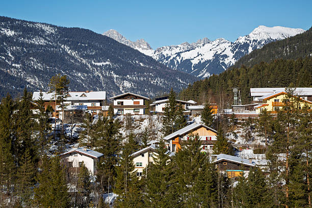 An idyllic winter mountain landscape with a village under blue sky on a sunny day in Austrian Alps.