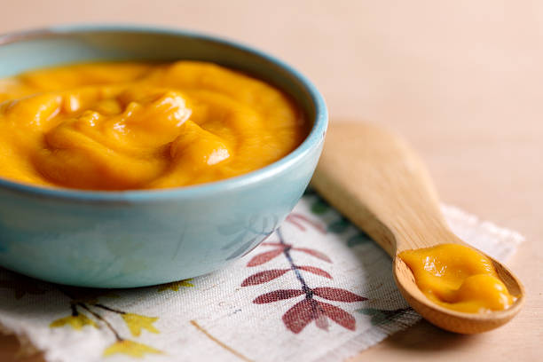 Mashed pumpkin in a bowl with wooden spoon.