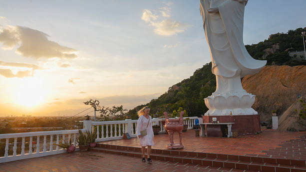 Mature woman explores Buddhist temple on mountain at sunset, Trung Khanh, Phan Rang