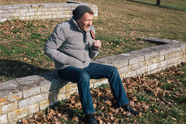 Man eats ice cream on stick on cold winter day outdoors in public park