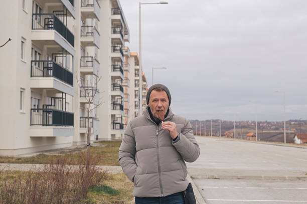 Man eats ice cram on stick outdoors in the city on cold winter day