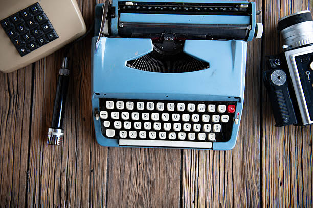 Top view of classic blue typewriter on wooden desk. Retro writing, creativity and storytelling concept.