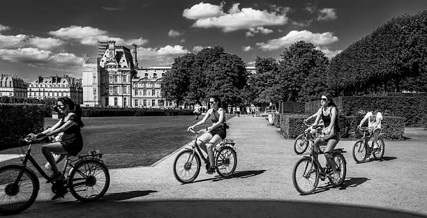Paris, France - July 17, 2015:  On the grounds of the Louvre Museum is the Tuileries Garden.  Cyclists ride their bicycle in this area on a beautiful summer day.