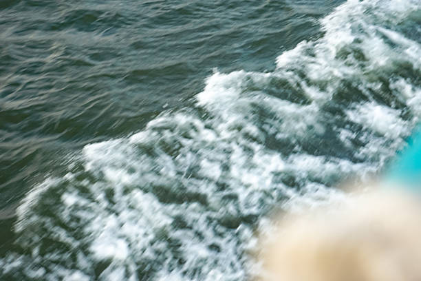 Foamy boat wake trailing across dark green water surface in motion.