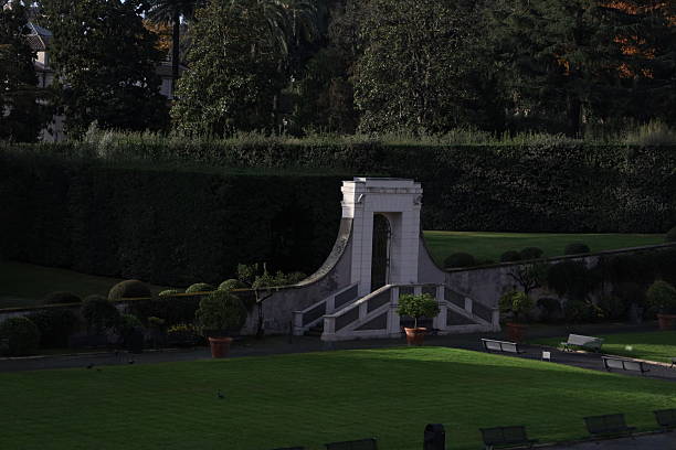 Formal garden with stone stairway and arched doorway surrounded by hedges and trees inside Vatican Gardens