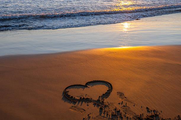 Red heart shape on the beach at sunset.