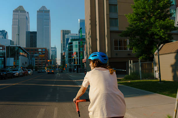 Woman in helmet riding bicycle through downtown in Calgary, Canada  in summer