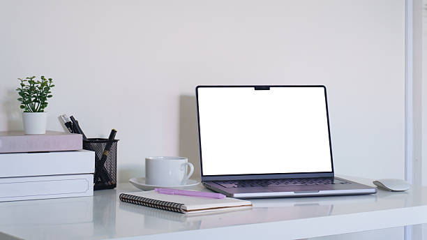 istock Minimal workspace with laptop, notebook, and coffee cup on clean white desk. 2259671517
