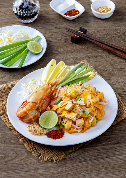 Pad Thai with large prawns, served on a white plate.