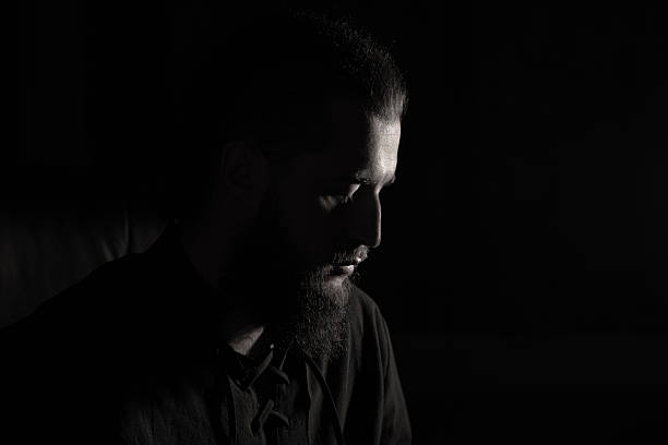 POrtrait of a man with a wet face. Black and white Picture. The face is only partially illuminated