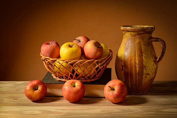 Still life, fresh apples in a wicker basket and a ceramic jug