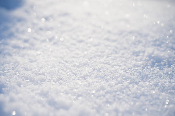 High key macro of fresh snow surface with sparkling ice crystals and soft bokeh highlights, clean winter light and pale blue tones creating minimal abstract background with copy space