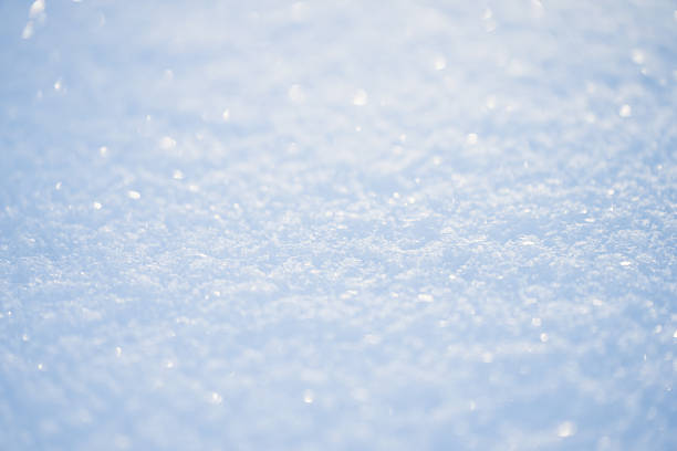 Soft focus macro of fresh snow surface with sparkling ice crystals, bright winter light and smooth pale blue tones, minimal abstract cold season background texture with copy space