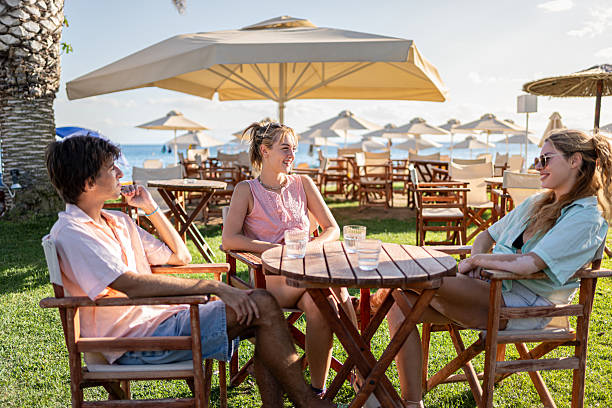 happy senior friends relax in outdoor cafe by seaside