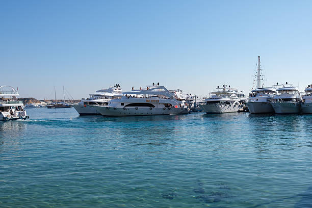 Sharm El Sheikh, Egypt - January 25, 2026: Luxury yachts move through clear blue waters in a marina with several boats docked under a bright sunny sky