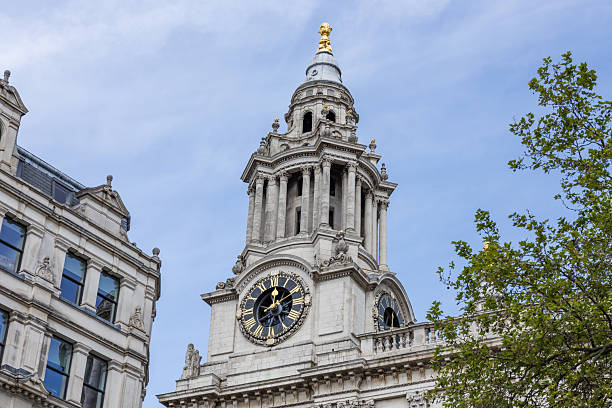 A detailed view of the ornate clock tower at St. Paul's Cathedral in London with clear blue skies and surrounding historical buildings. London, UK, 21 April 2024
