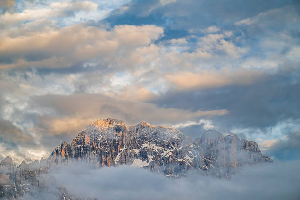 Monte Civetta mountain in the Dolomites surrounded by clouds during sunset after a beautiful springtime day. The Civetta is a prominent and major mountain of the Dolomites, and is popular amongst mountaneers to climb as its one of the highest rock formations in Europe.