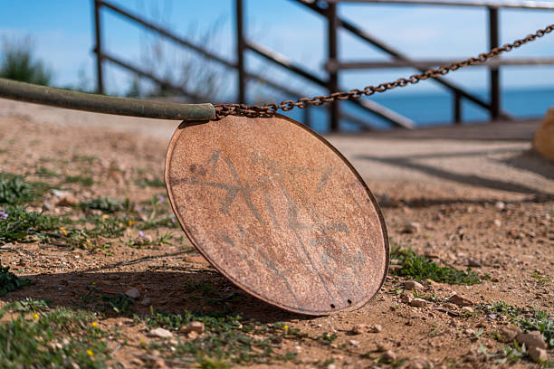 Close up of rusty metal sign plate hanging on chain near coastal path with sea in background abandoned barrier restriction concept