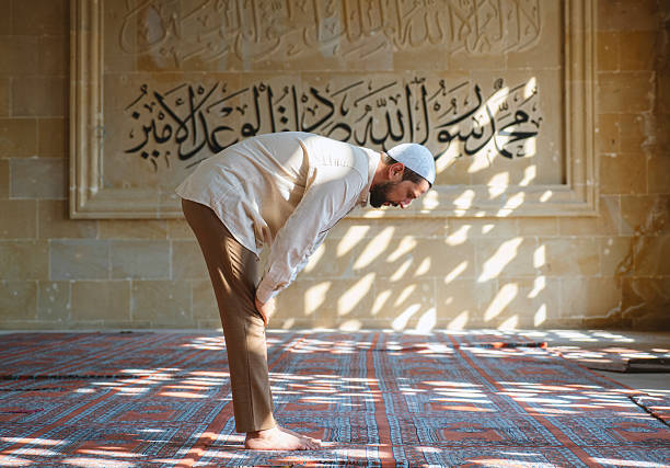 istock Muslim Man Praying in a mosque in front of Arabic Calligraphy 2259715029