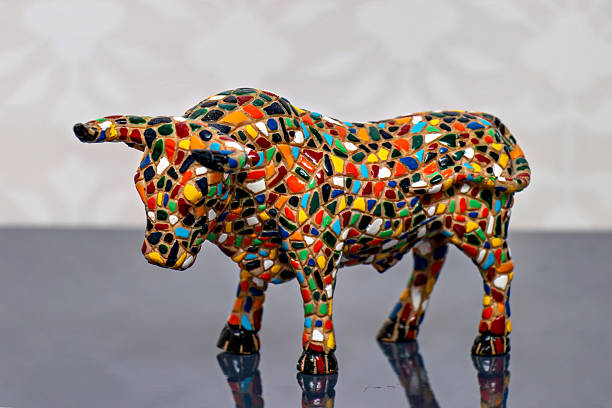 A colorful mosaic cow figurine on a reflective surface.