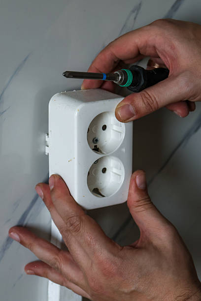 istock Electrician mounts an electrical outlet or socket to the wall showing it's the structure and connecting cables. 2259721805
