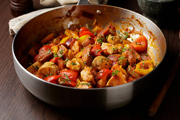 A close-up of a homemade, healthy, Cajun-inspired one-pan dish featuring spicy Spanish sausage, sweet peppers, tomatoes, and diced chicken breast.