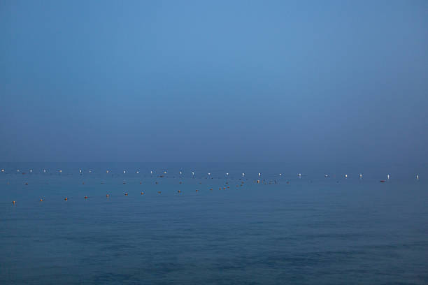 Calm sea at twilight with buoys creating visual lines to the horizon