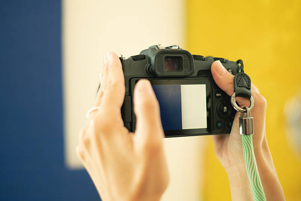 Close-up on female photographer's hands while  she holds her analog camera and adjust it before taking photos in a beautiful vineyard during her travel adventure.