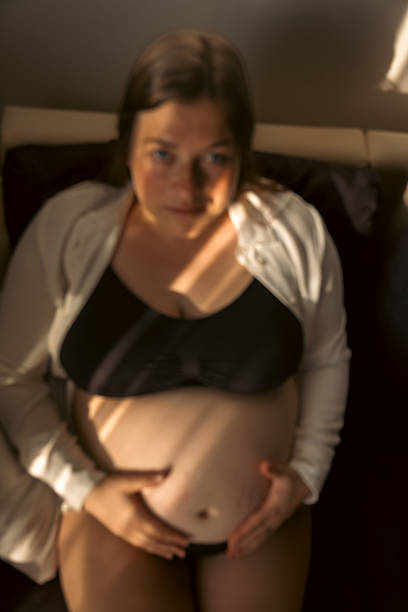 Young woman sitting on the sofa and being showered by last rays of light in Summer