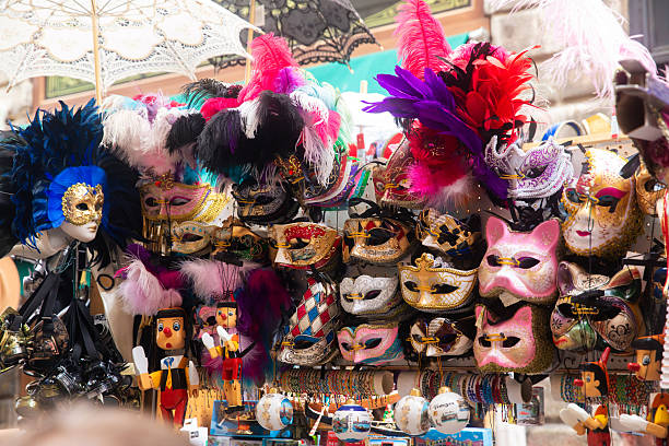 Colorful traditional masks displayed at a street market in Venice, Italy. The assortment includes handcrafted Venetian carnival masks, decorated with feathers, gold details, and vibrant colors, reflecting the city’s historic craftsmanship and festive traditions. The scene represents local culture, tourism, and the visual identity of the Venice Carnival, one of the most iconic cultural events in Venice.