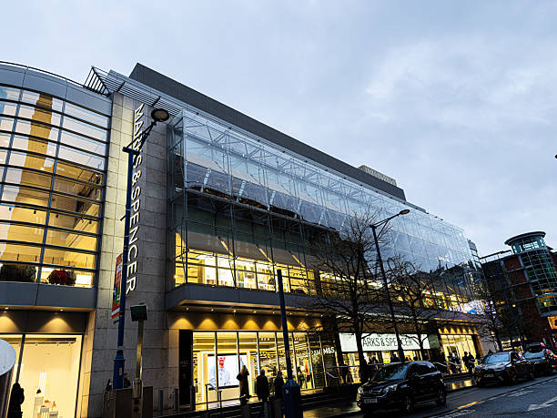 Manchester, UK - January 21, 2026: Busy Manchester Marks Spencer shopping centre with glass exterior and stores, evening lights, and urban activity.