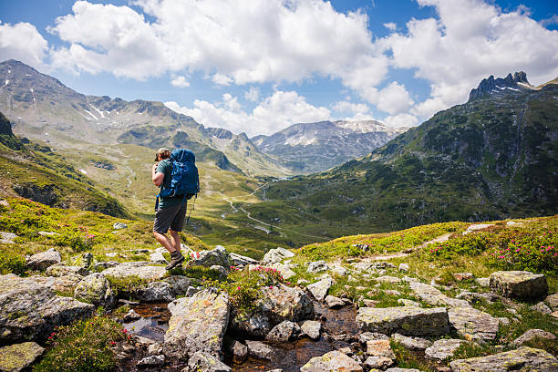 Male backpacker hiking through rocky valley in austrian Alps mountains. Active summer vacation in Styria, Austria with scenic mountain view