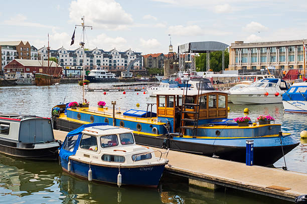 Bristol UK: 28th July 2025: Boats docked at Bristol Harbourside with buildings and water in the background during a sunny day