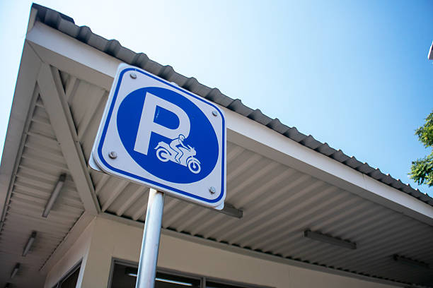 A blue motorcycle parking sign stands prominently against a clear sky, providing essential information for riders about designated parking areas in urban settings.