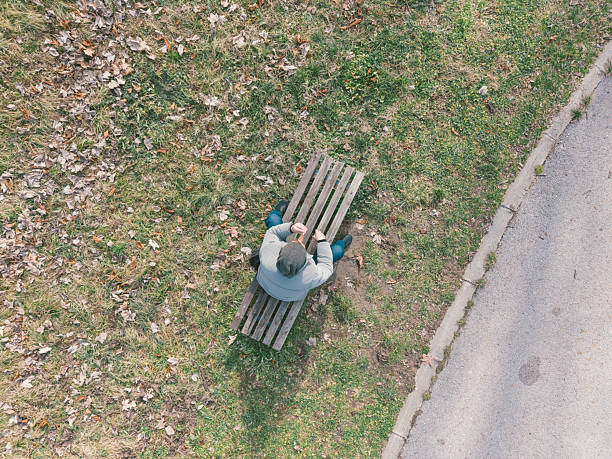Red Bank, New Jersey, USA-September 19, 2025: A person sits alone on a wooden bench facing the Navesink River.
